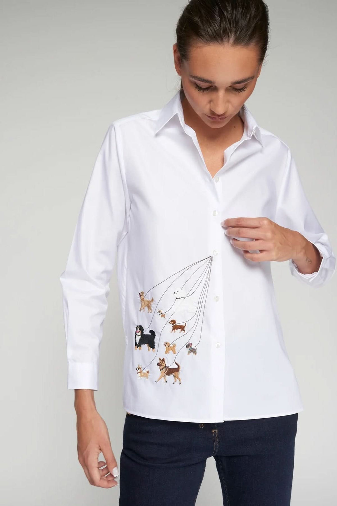 Person wearing chemise brodée de chiens, showcasing elegant dog embroidery on white classic shirt with structured collar and button closure.