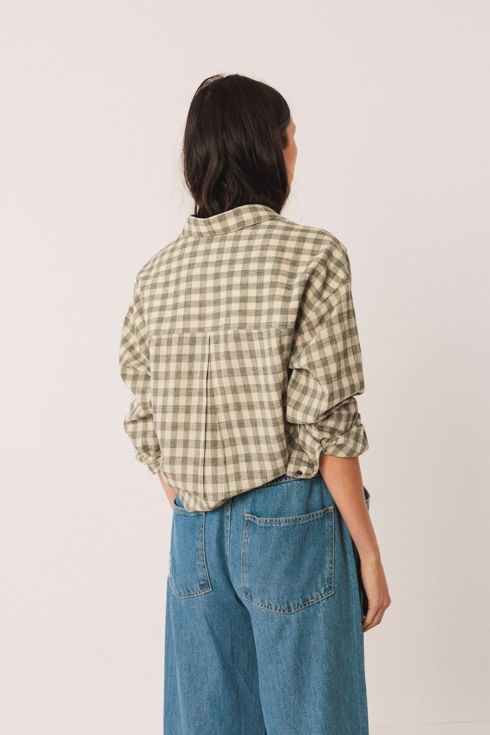 Chemise à carreaux verte vue de dos, manches retroussées, style décontracté avec un look moderne.