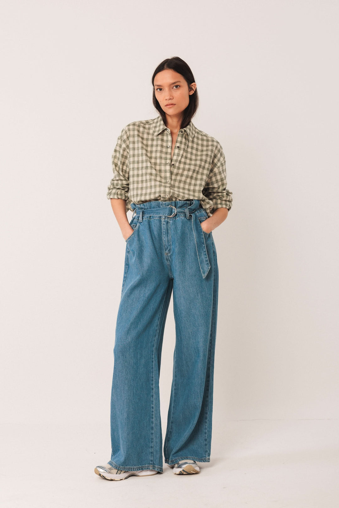 Mode féminine : chemise à carreaux verte avec pantalon large, look décontracté et moderne.
