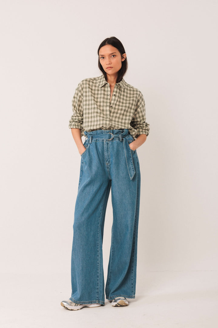 Mode féminine : chemise à carreaux verte avec pantalon large, look décontracté et moderne.