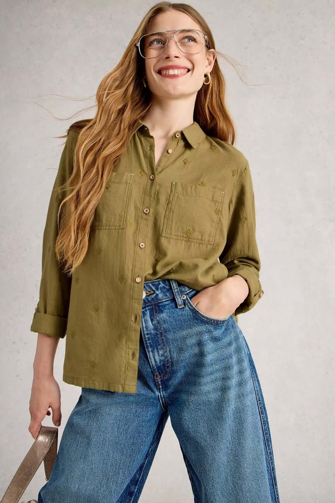 Femme portant une chemise en coton manches retroussables décontractée avec deux poches poitrine et jean, style confortable et moderne.
