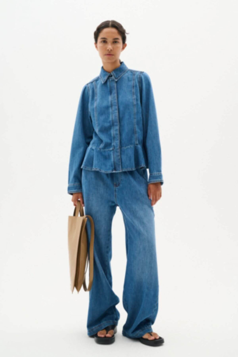 Femme portant la chemise en denim Sophina avec coupe péplum, associée à un pantalon en jeans pour un look décontracté.