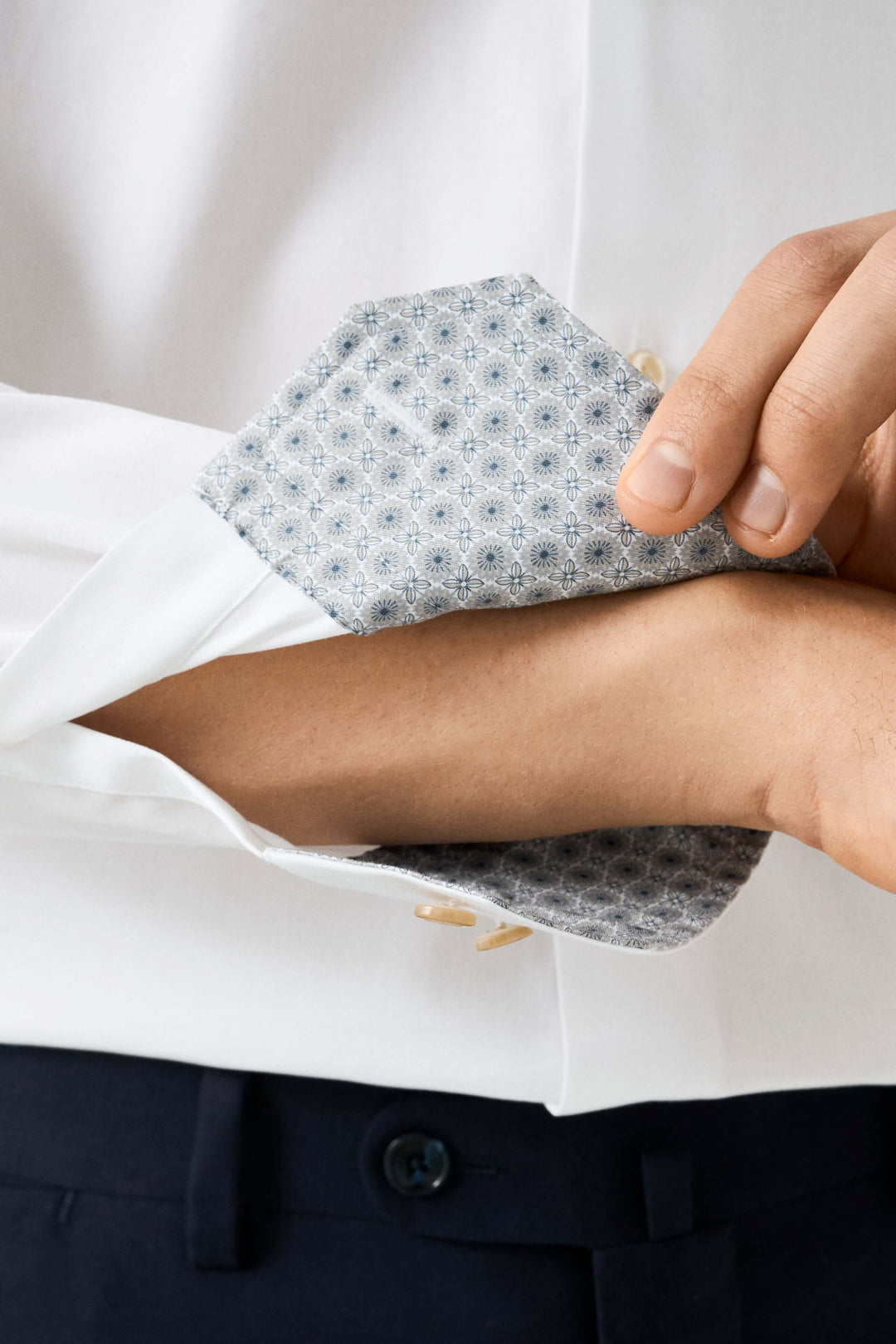 Chemise habillée blanche avec poignets imprimés en bleu, détails élégants et boutons nacrés dorés.