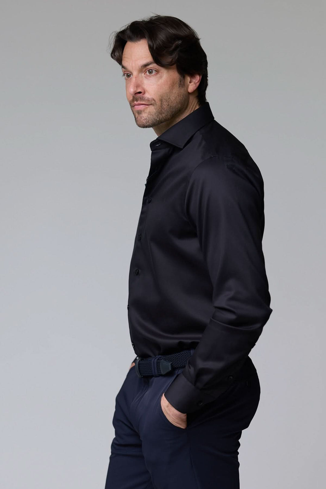 Homme portant une chemise infroissable de base satinée noire, coupe ajustée élégante, pour un look sophistiqué et professionnel.