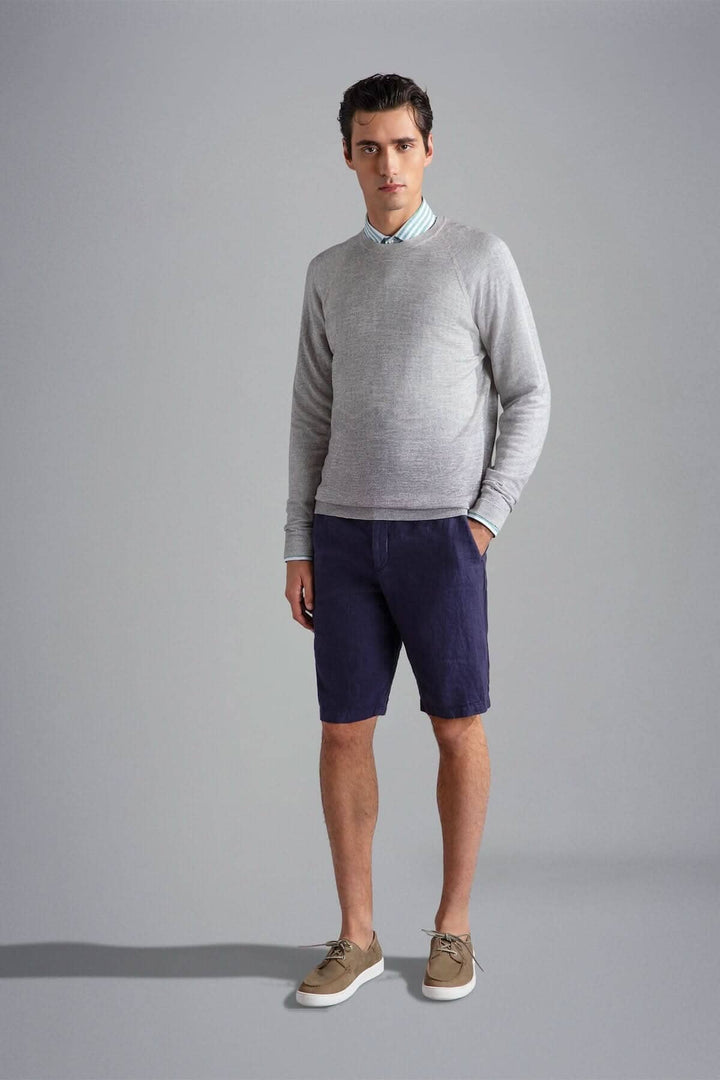 Homme en pull gris, chemise à rayures et short bleu marine, stylé et décontracté.