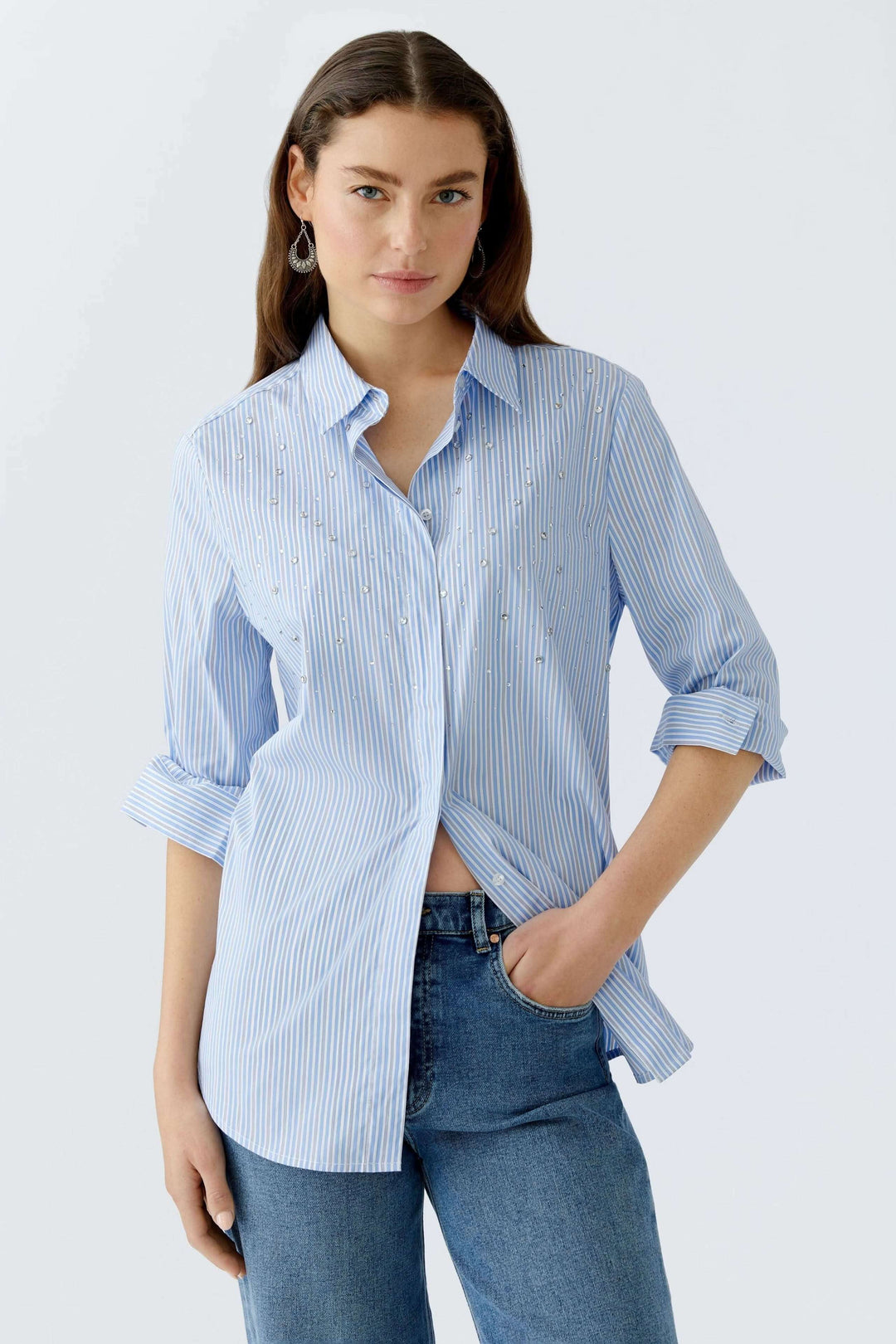 Femme portant une chemise longue rayée avec détails galets, coupe décontractée, ourlet arrondi, mélange coton.