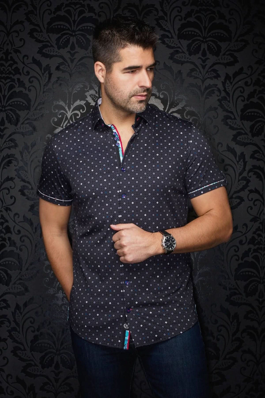 Homme portant une chemise à manches courtes Apollo avec imprimé géométrique sur fond noir et détails colorés.