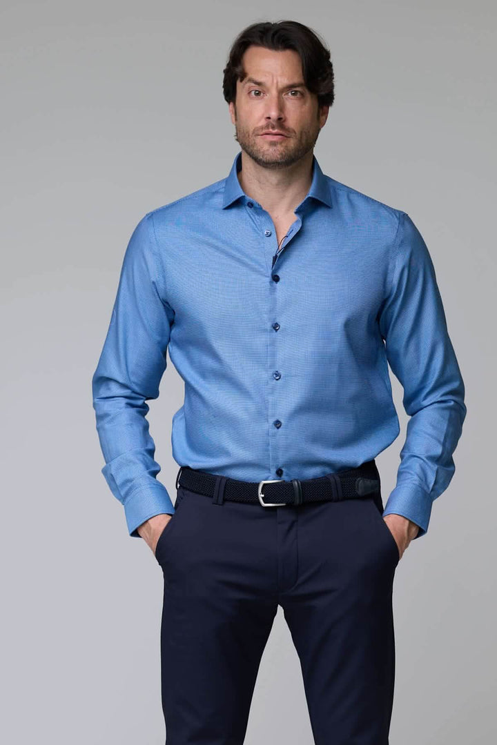 Homme portant une chemise à micro-motif texturé bleue à manches longues, coupe ajustée, col classique, tenue élégante et confortable.