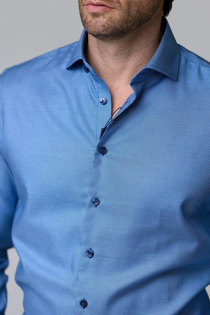 Chemise à micro-motif texturé, bleu, coupe ajustée, portée par un homme, offrant élégance et confort idéal pour le bureau ou occasions chics.