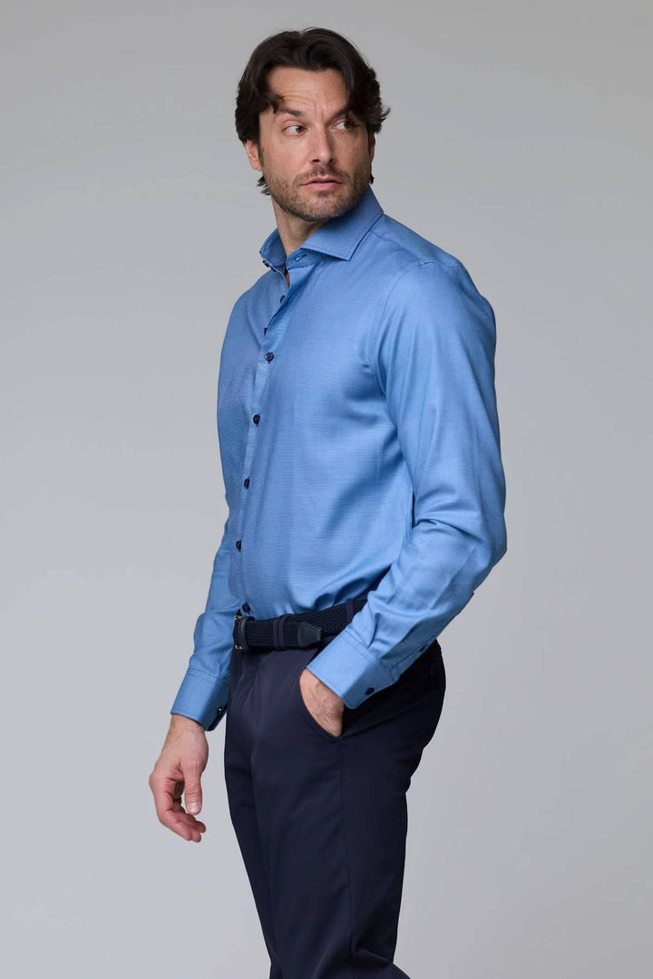 Homme portant une chemise à micro-motif texturé, coupe ajustée, couleur bleue, idéale pour le bureau ou une occasion chic.