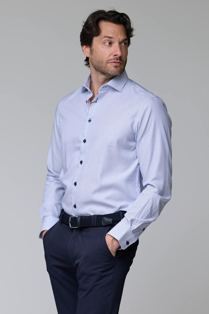 Homme portant une chemise à motif géométrique avec manches longues et boutons contrastants pour un look élégant.