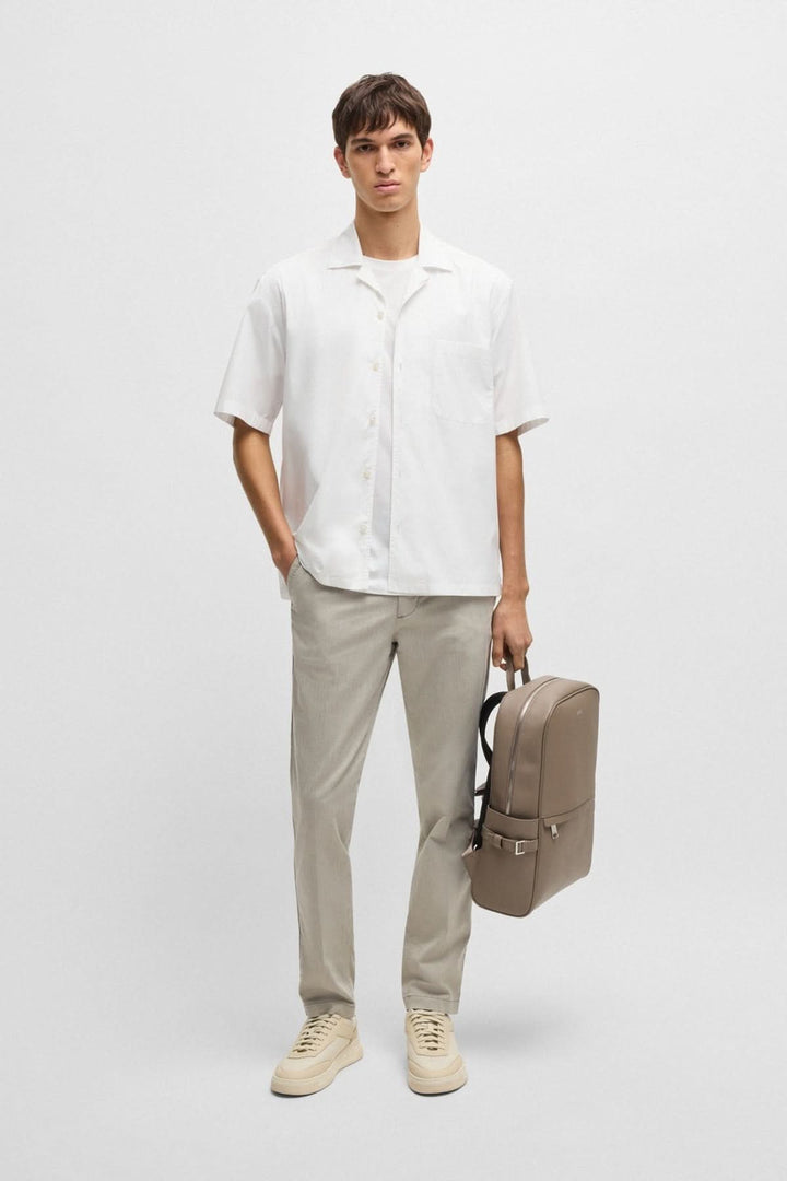 Homme portant une chemise oversize blanche élégante et un sac à dos beige, vêtu d&