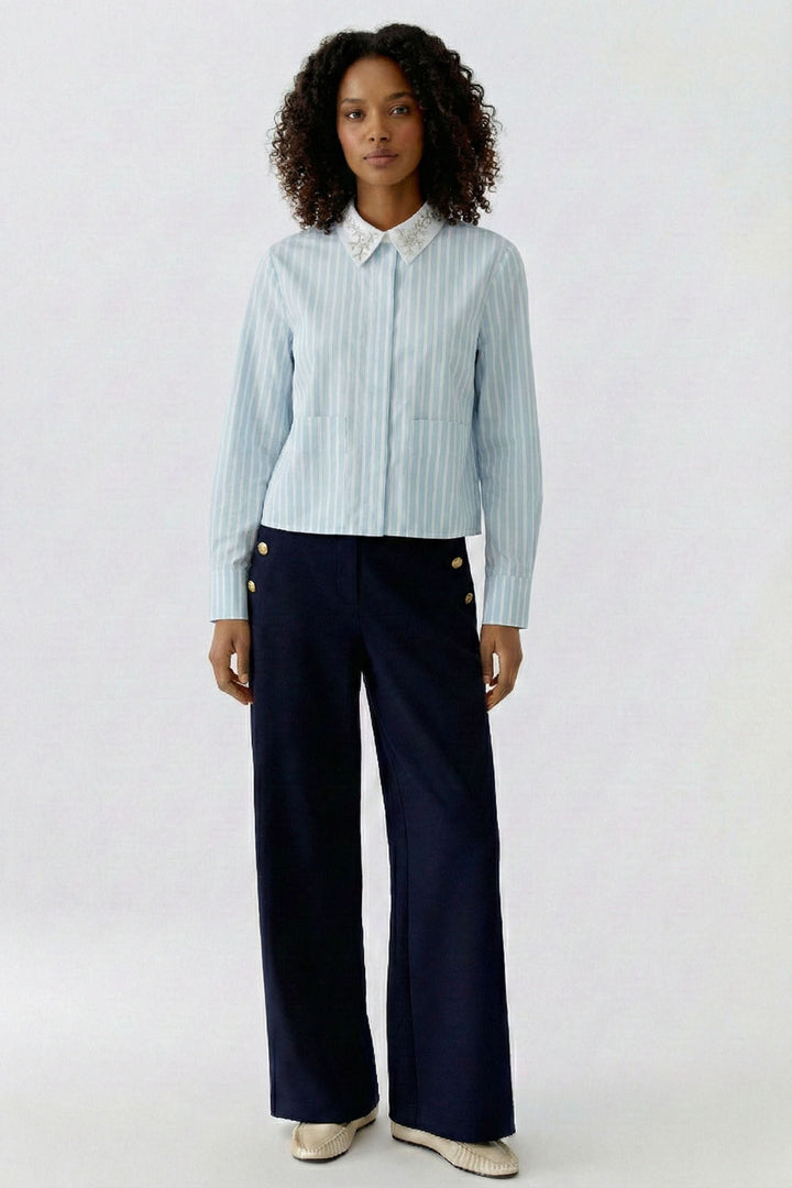 Femme portant une chemise rayée à col brodé, élégante et polyvalente, idéale pour le bureau ou un look habillé.