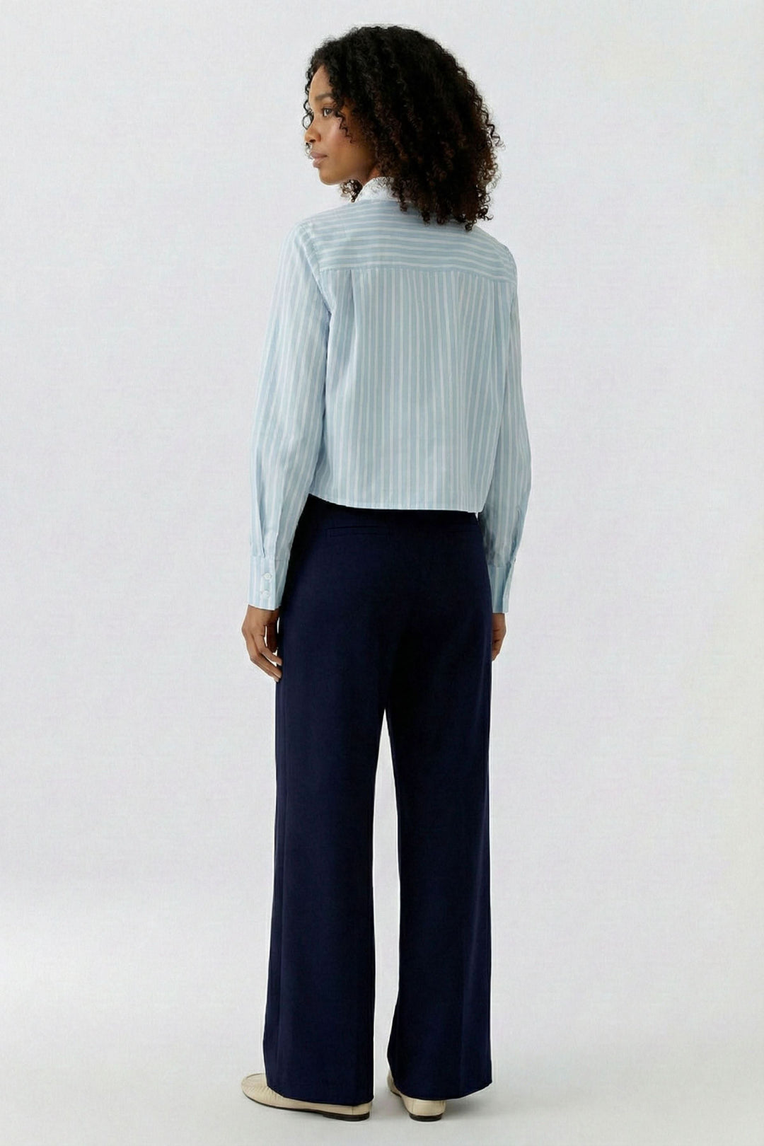 Femme portant une chemise rayée à col brodé, vue de dos, élégante et raffinée. Idéale pour le bureau ou un look habillé.
