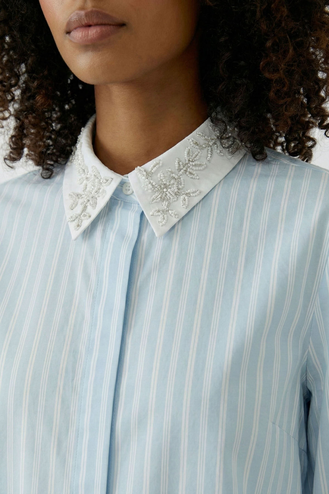 Chemise rayée à col brodé avec broderies délicates, coupe élégante et polyvalente pour un look chic et confortable, décris moi le produit en français.