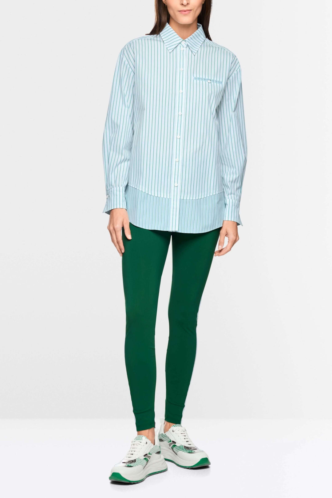 Chemise rayée en coton portée avec pantalon vert, affichant une silhouette moderne et allongée, idéale pour un look professionnel ou décontracté.