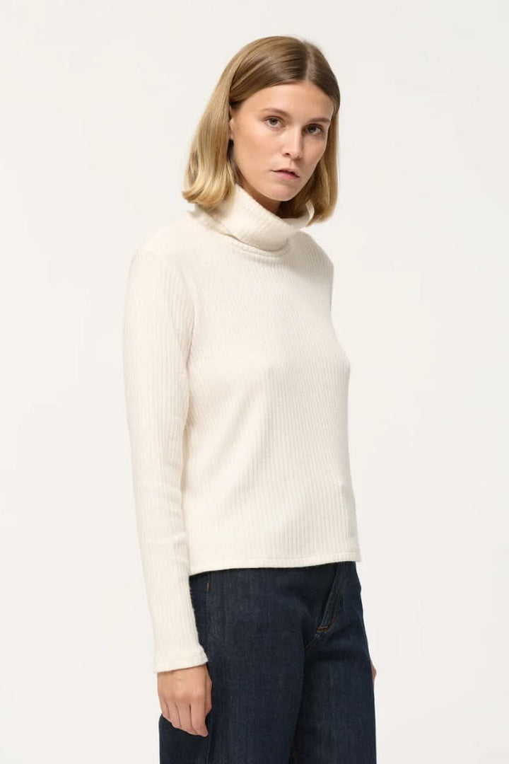 Col roulé côtelé en jersey crème, manches longues et style décontracté, parfait pour superposer.