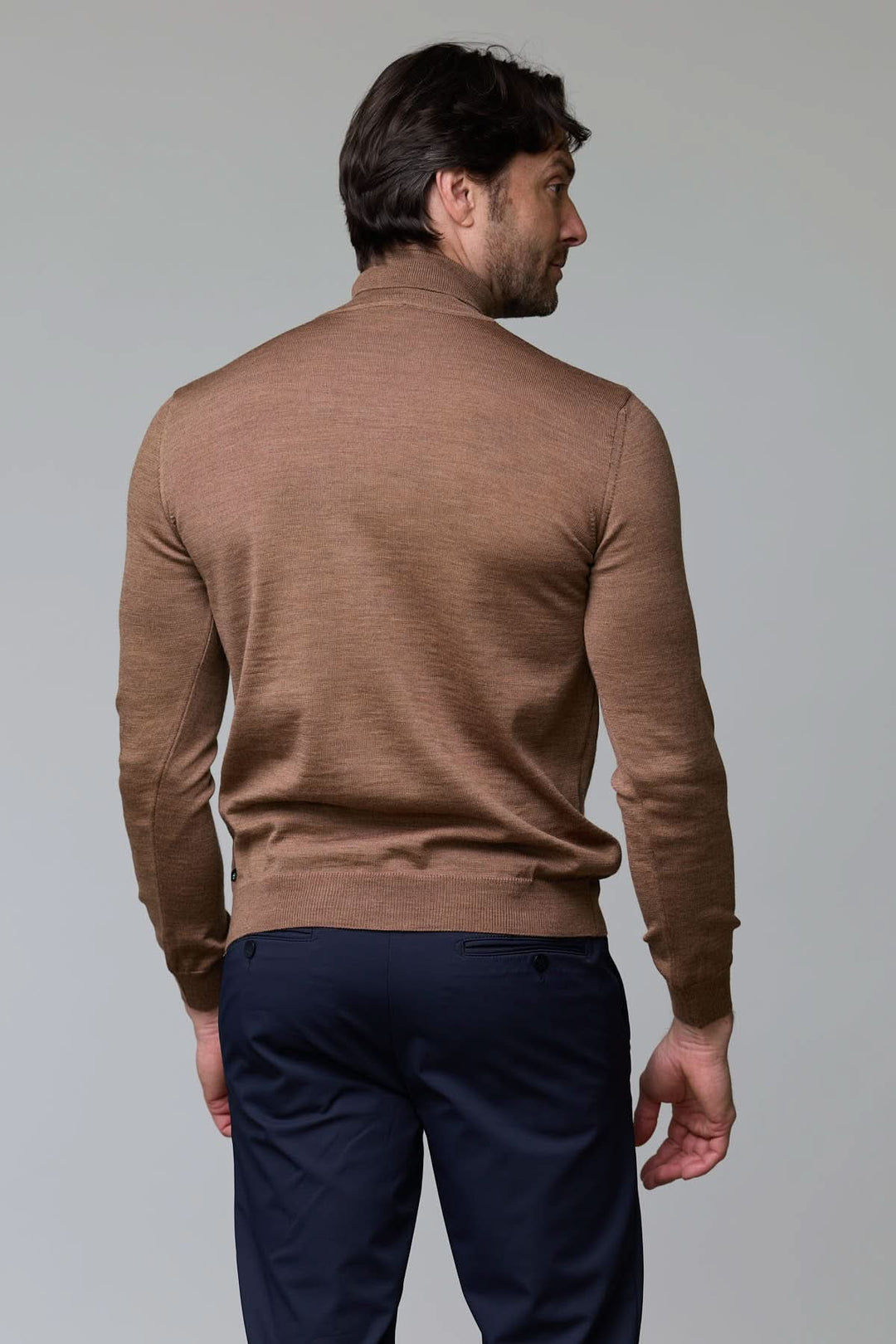 Homme portant un col roulé en laine mérinos marron, coupe ajustée, vue de dos. Décris moi le produit en français.
