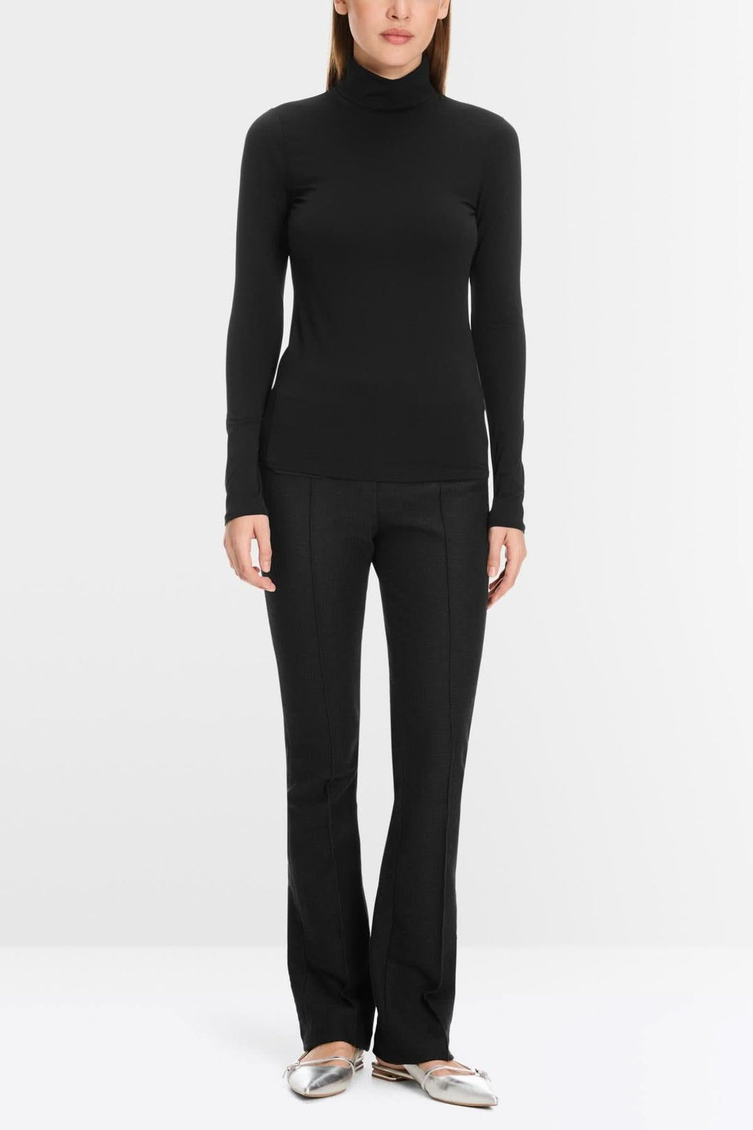 Femme portant col roulé mince noir, design épuré avec étoffe extensible, offrant confort optimal et silhouette légèrement cintrée.