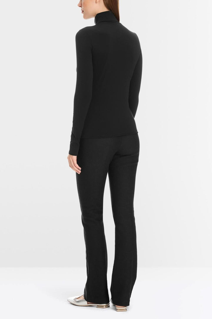 Femme portant un col roulé mince noir, tissu extensible, doux, coupe cintrée, sous un veston ou seul, confort optimal.