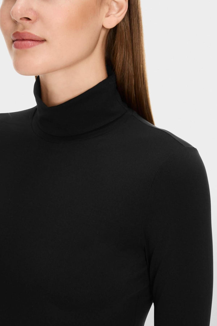 Col roulé mince noir sur mannequin avec col souple et tissu doux, coupe cintrée élégante. Design épuré, confort optimal.