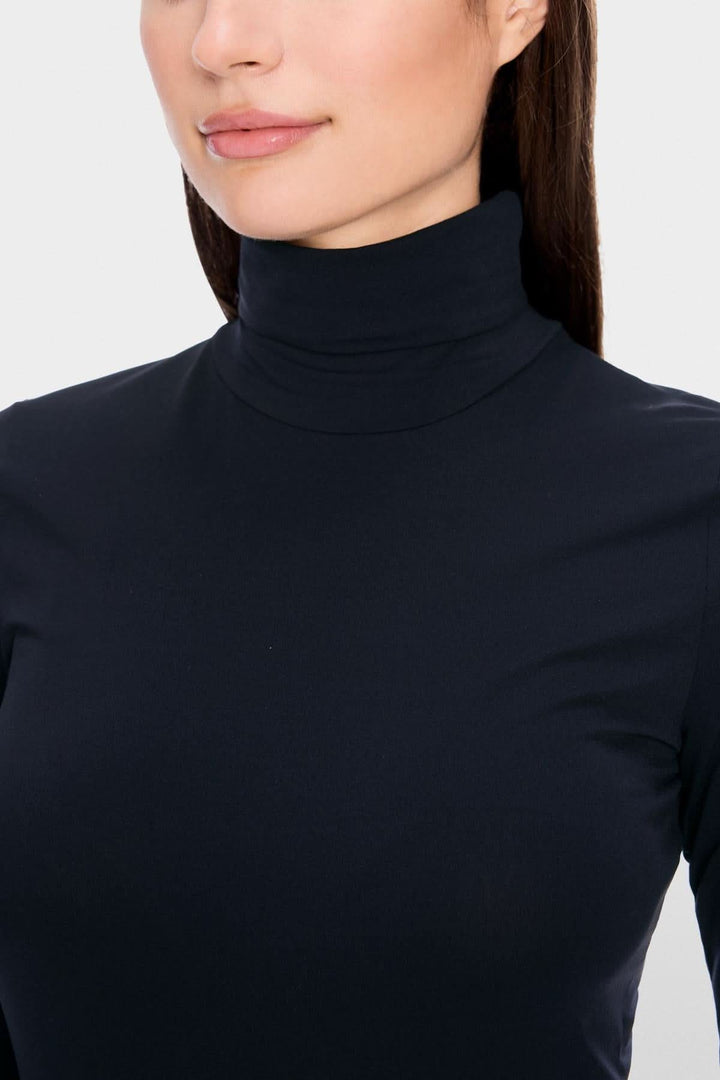 Femme portant un col roulé mince en tissu extensible et confortable, coupe légèrement cintrée, idéal pour superposition élégante.