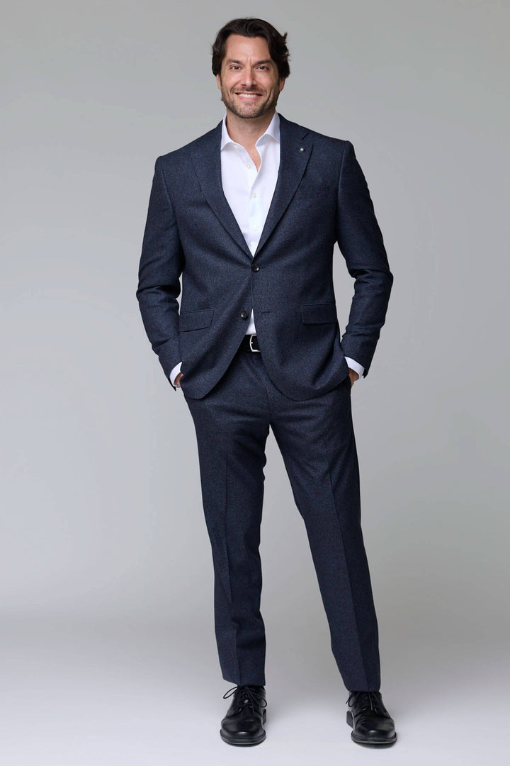 Homme portant un complet en laine texturée élégant et moderne, coupe ajustée parfaite pour occasions professionnelles et habillées.
