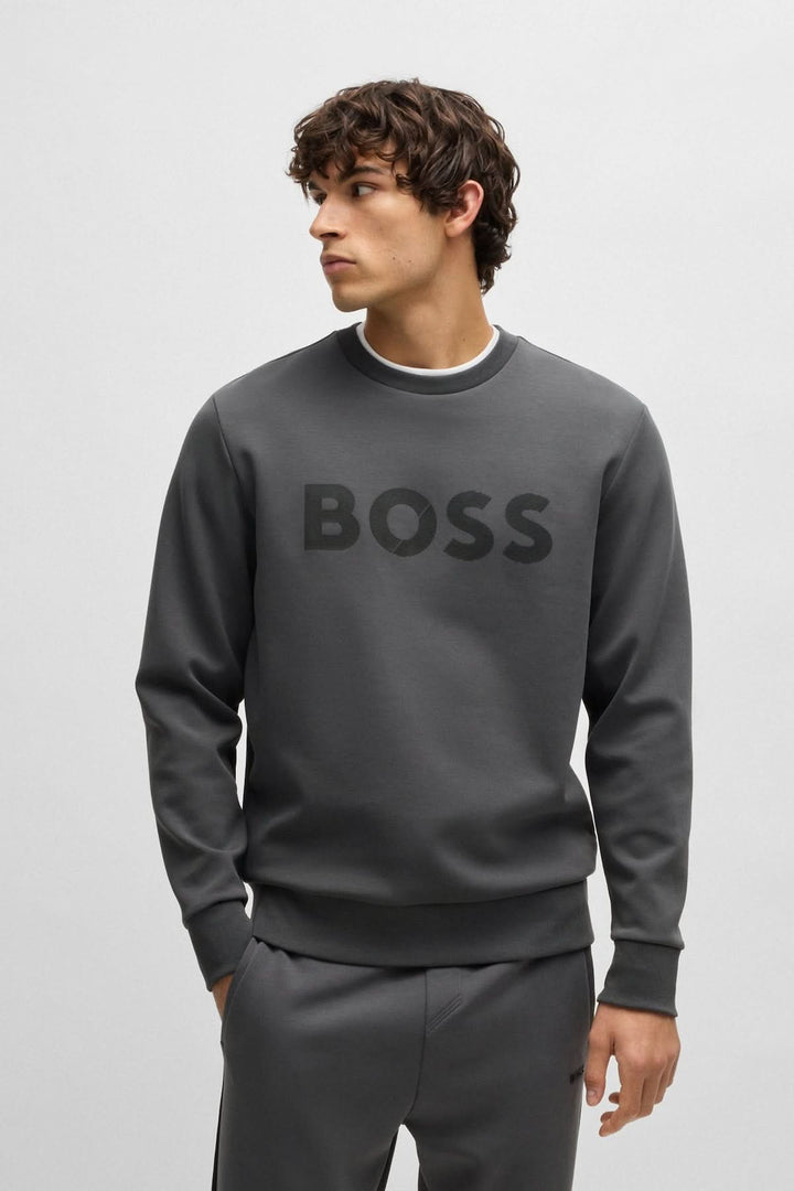 Homme portant un chandail à encolure ras du cou gris BOSS, style décontracté avec logo en avant.