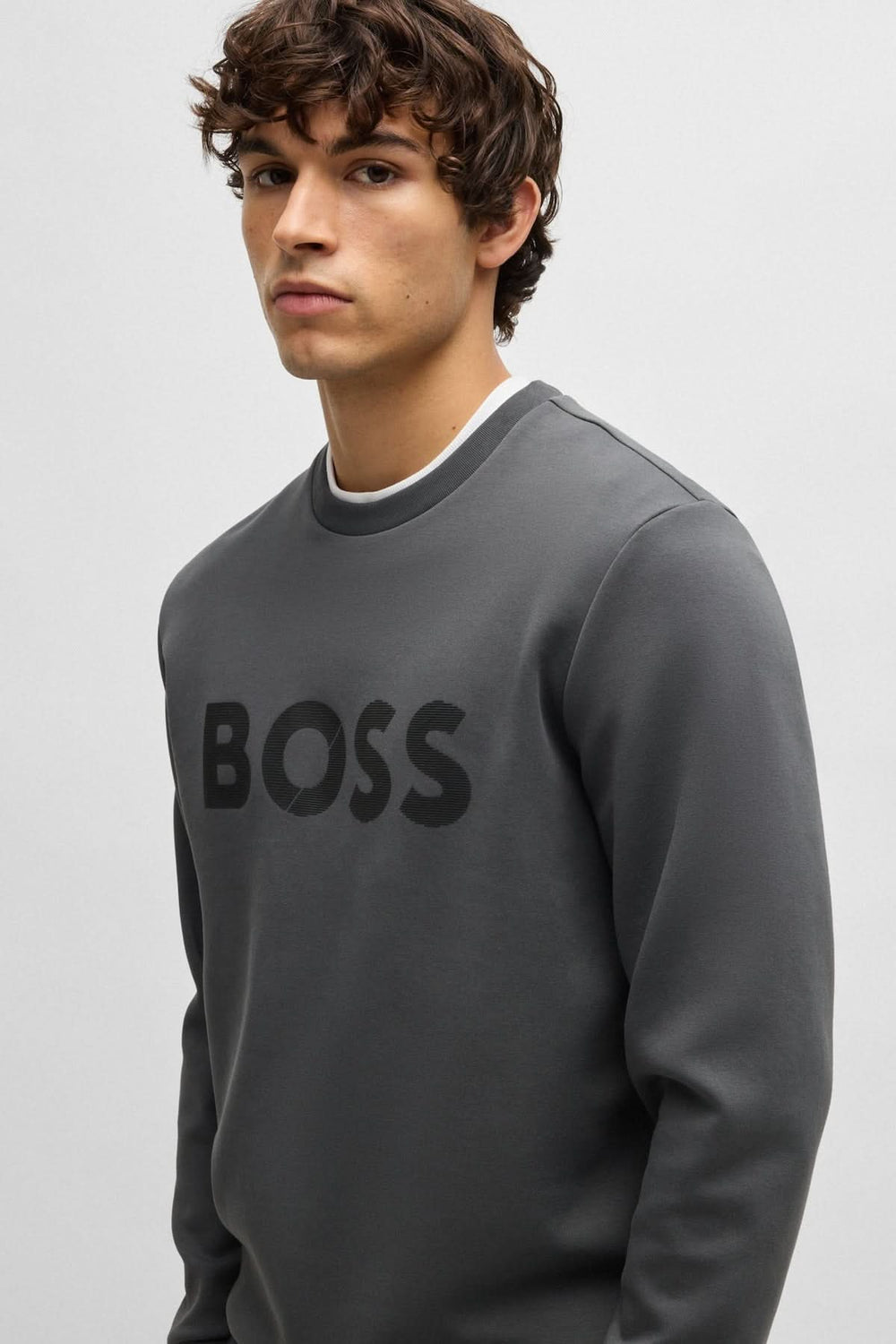 Homme portant un chandail gris BOSS à encolure ras du cou, style moderne et décontracté.