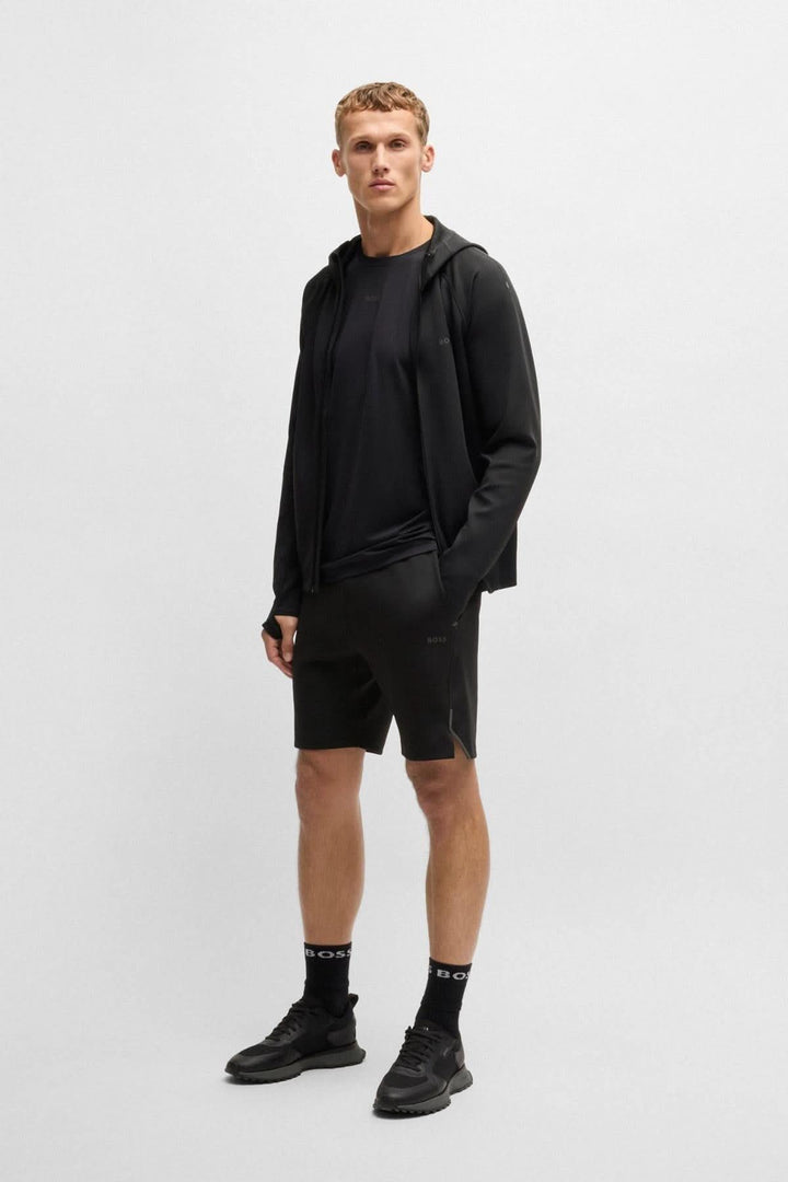 Homme portant une veste sportive BOSS avec capuche, t-shirt et short pour entraînement.