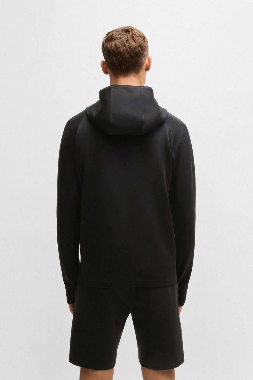Homme vu de dos portant un coton ouaté sportif noir avec capuche, idéal pour l'entraînement.