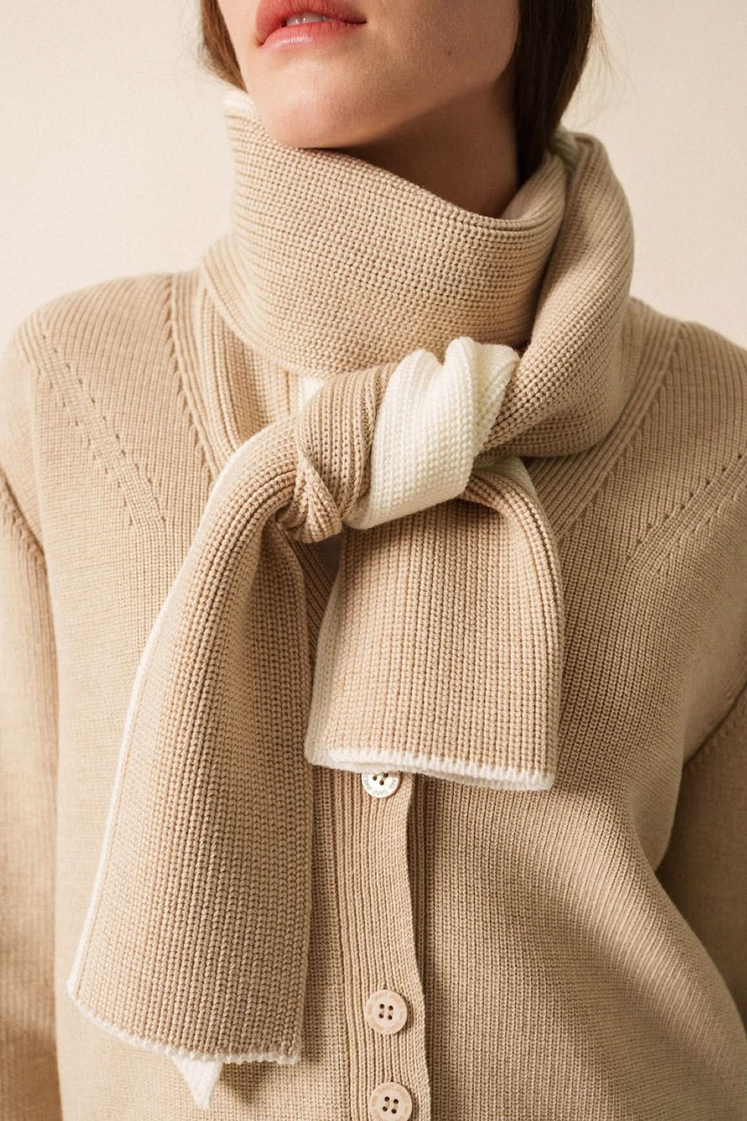 Foulard en maille bicolore, douceur et élégance décontractée, noué autour du cou pour un look cosy.
