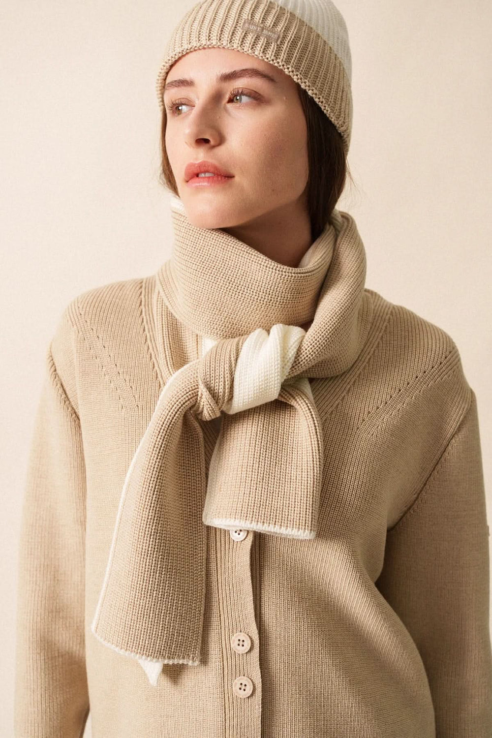 Foulard Canoe en maille bicolore, doux et élégant, porté avec un pull beige et un bonnet assorti.