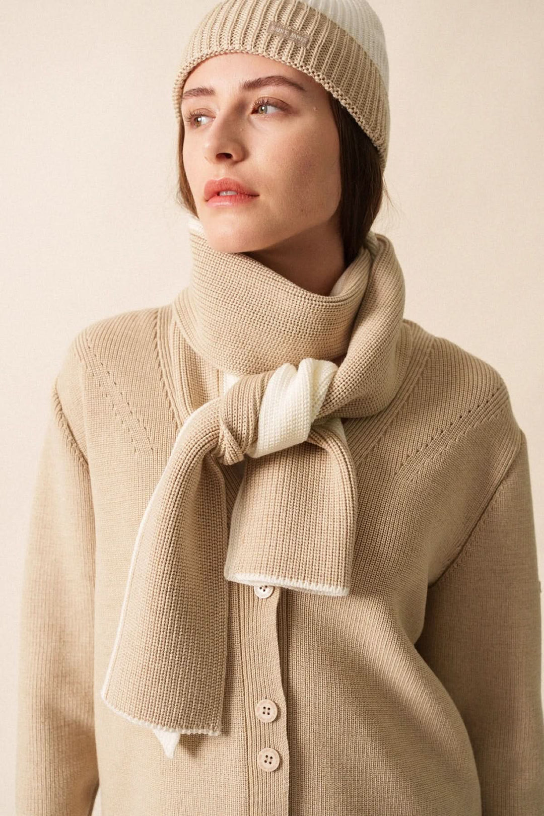 Foulard Canoe en maille bicolore, doux et élégant, porté avec un pull beige et un bonnet assorti.