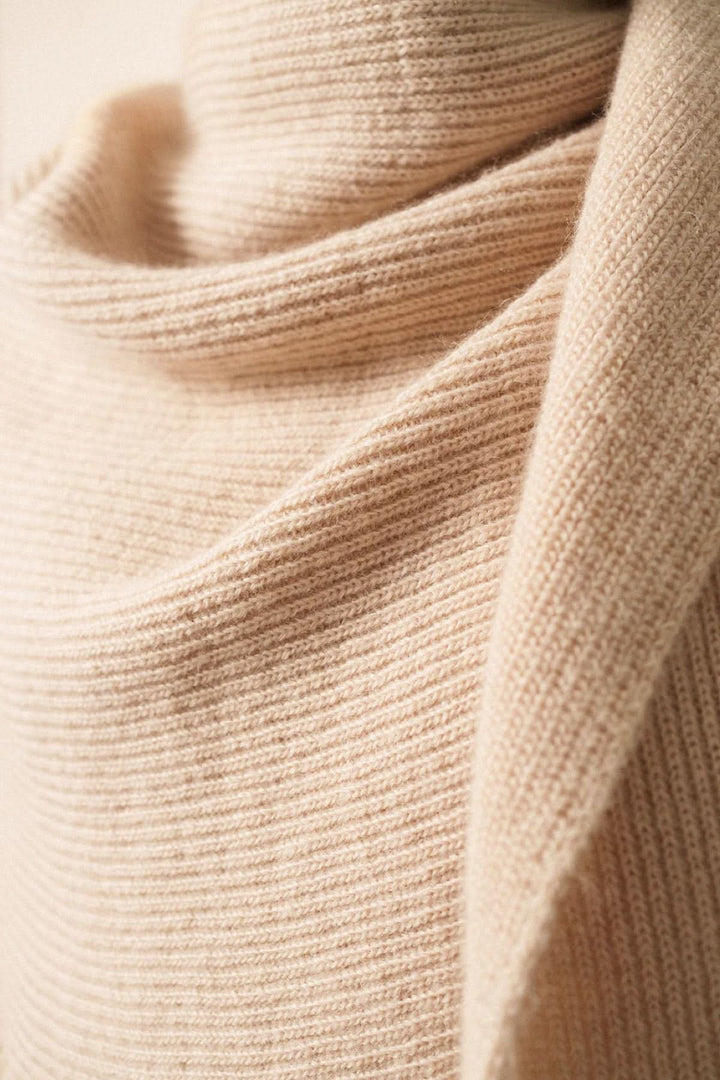 Foulard en maille douce couleur beige, avec texture côtelée, idéal pour un look cozy ou élégant.
