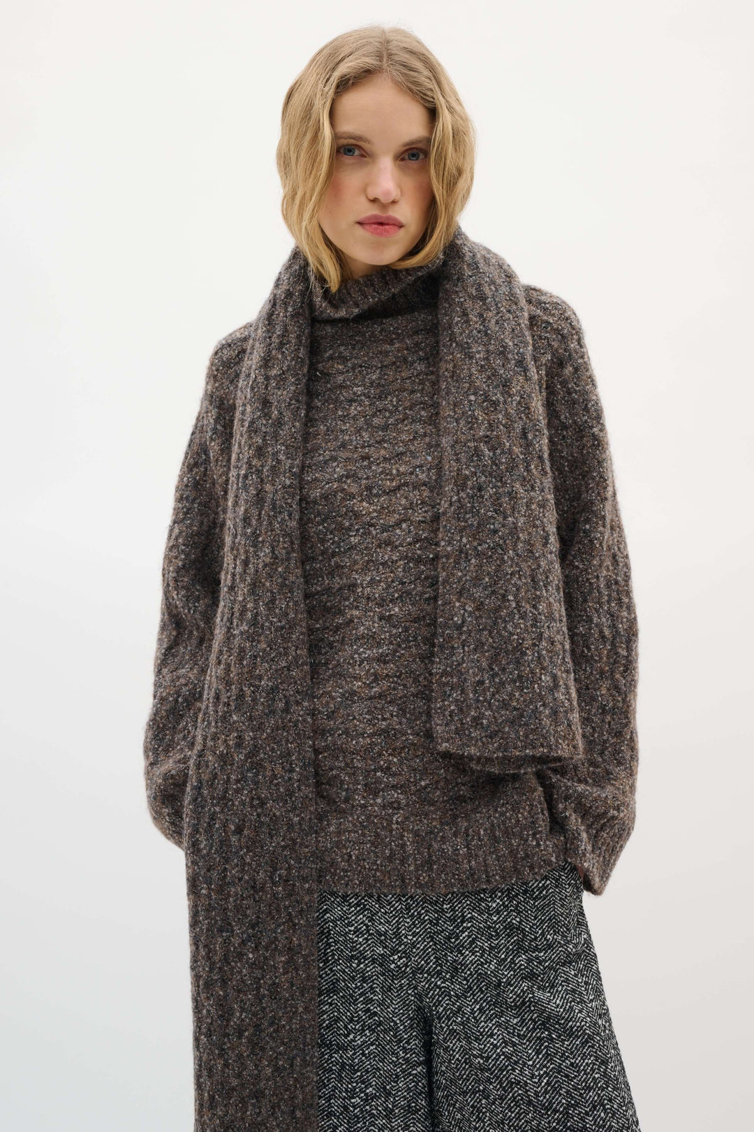 Foulard Graia en maille texturée porté sur un manteau, ajoutant chaleur et confort à une tenue élégante et moderne pour la saison froide.