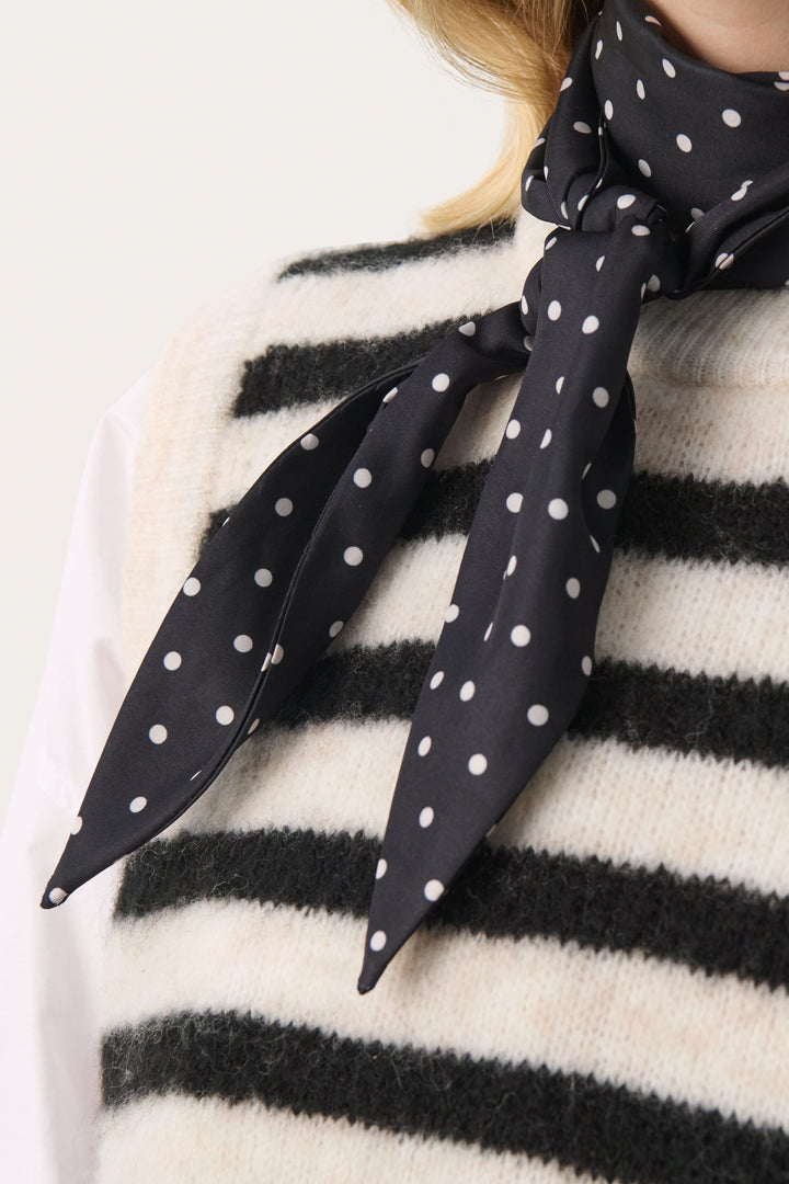 Foulard Lupa à pois noir élégant porté avec un pull rayé, ajoutant une touche féminine et intemporelle.