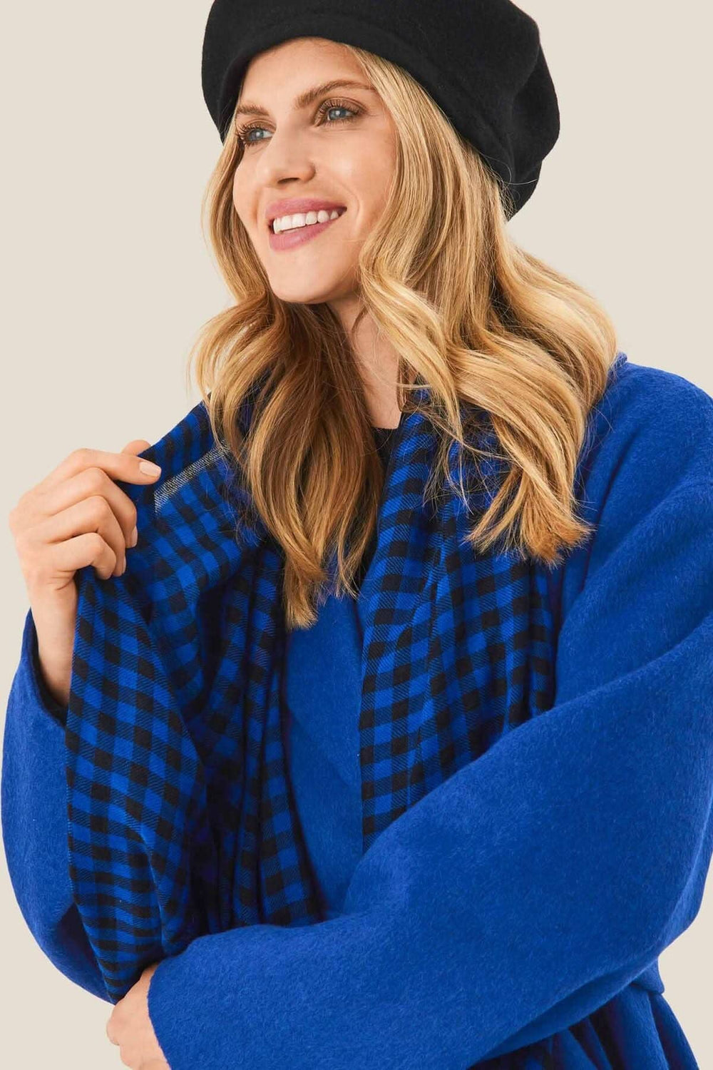 Foulard à carreaux noirs et bleus porté avec élégance, ajoutant du style et du confort à la tenue.