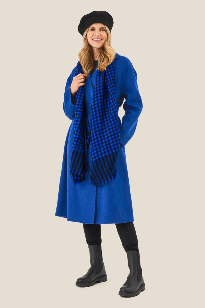 Foulard à carreaux noirs et bleus porté avec une robe bleue, complété par un béret noir.
