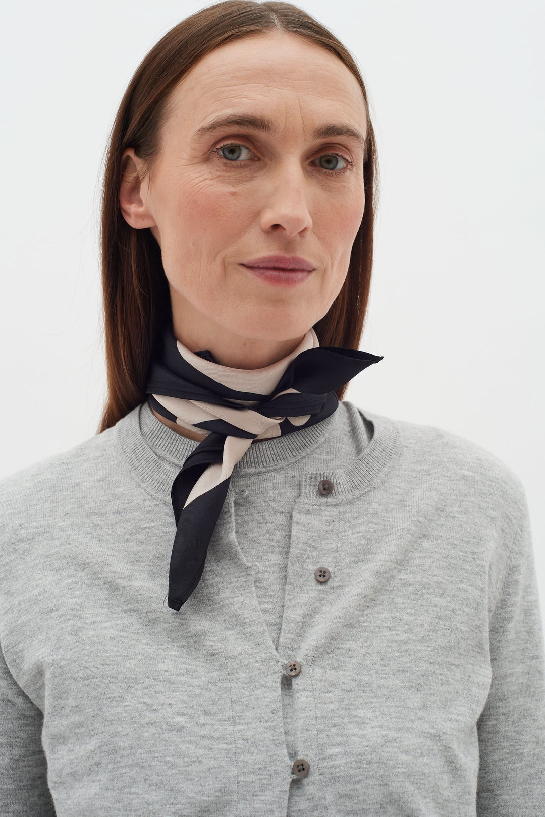 Foulard de soie Rafiq porté autour du cou, ajoutant une touche élégante à une tenue classique.
