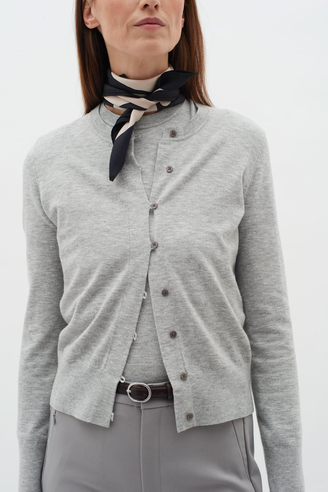 Foulard de soie Rafiq porté sous forme de nouer autour du cou, avec un cardigan gris élégant.