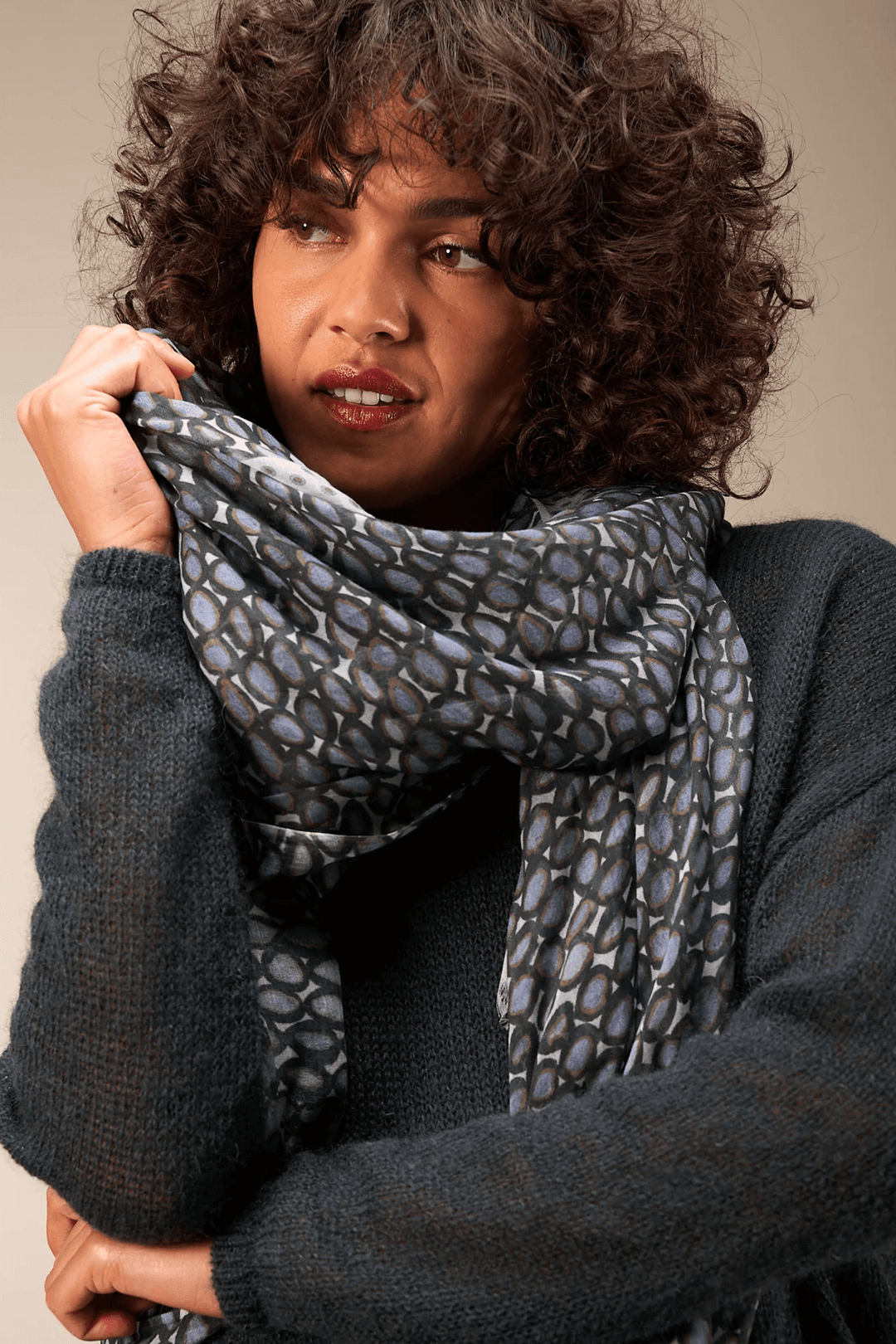 Femme portant un foulard imprimé enroulé autour du cou, ajoutant une touche sophistiquée à sa tenue.