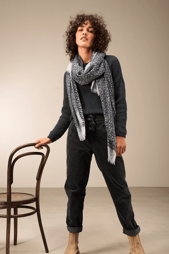 Femme portant un foulard imprimé sur un chandail uni, accessoire élégant et confortable, idéal pour un style sophistiqué.