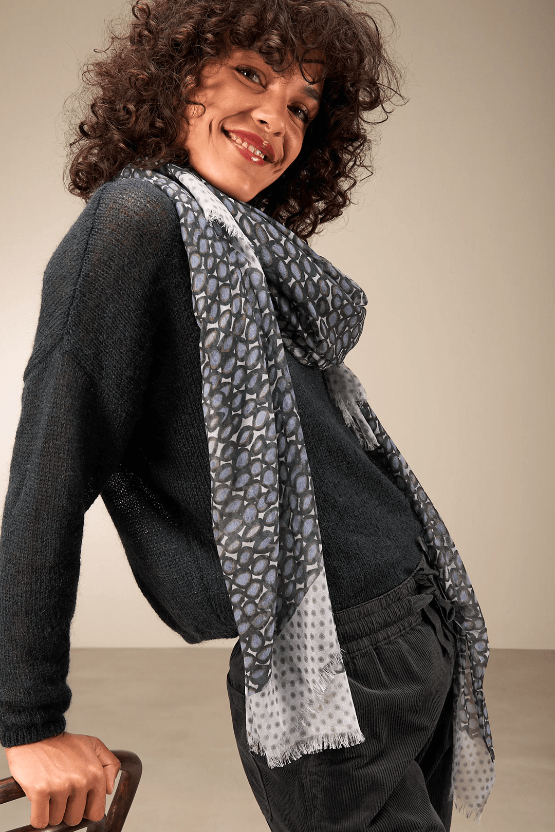 Femme souriante portant un foulard imprimé léger et fluide, idéal pour une touche de sophistication à votre style quotidien.