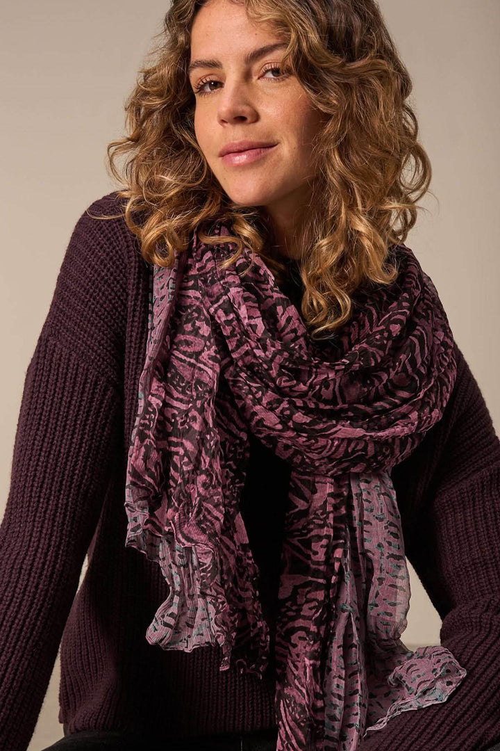 Foulard paréo en soie avec imprimé intégral, porté par une femme aux cheveux bouclés, ajoutant une touche d'élégance.