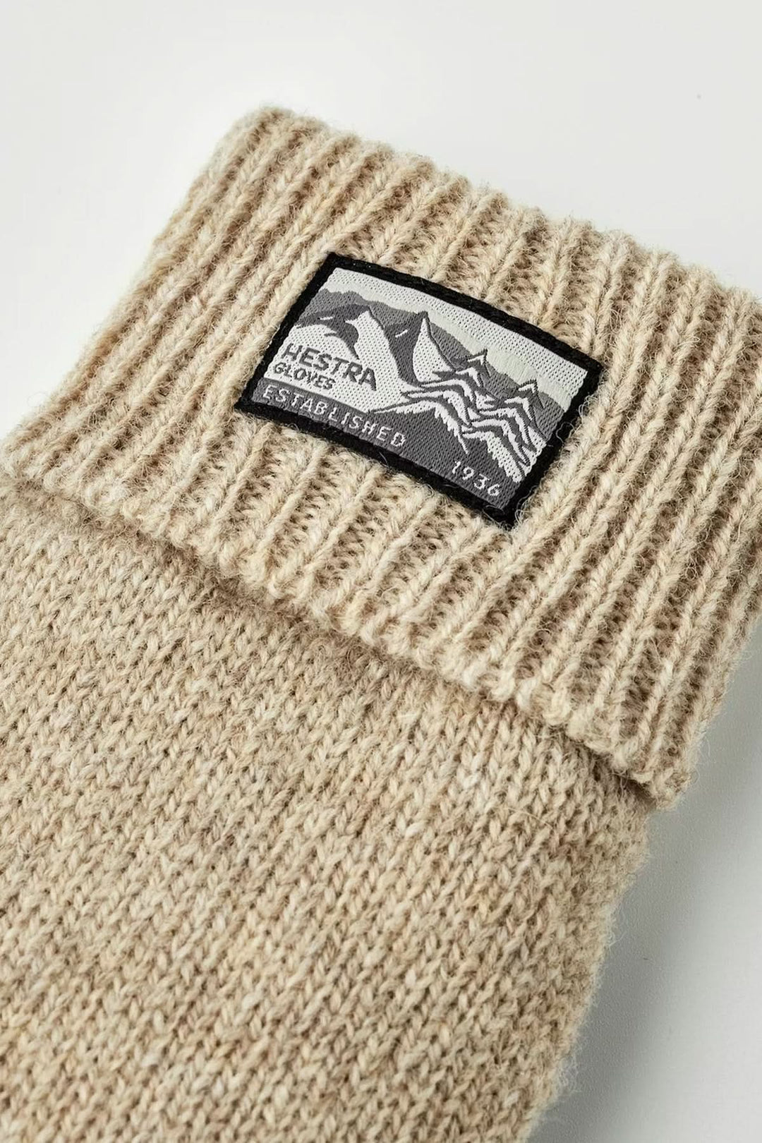 Ganst en maille beige avec détail de poignet côtelé et étiquette en gros plan, accessoire pour temps frais.