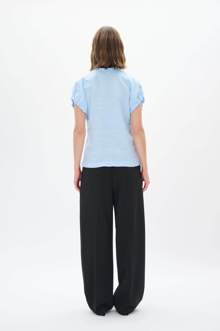 Haut en lin bleu clair vu de dos avec pantalon noir, style décontracté et élégant pour l&