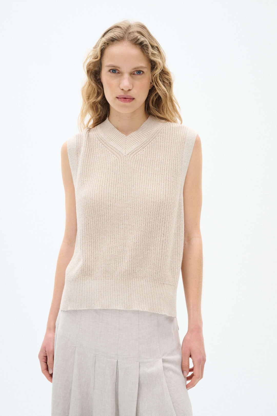 Pull sans manches beige en maille avec col en V, idéal pour superposer ou porter seul, style élégant et léger.