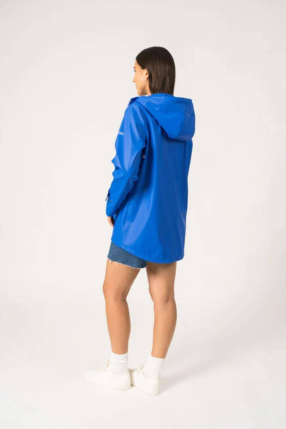 Femme portant un imperméable bleu Ste Gaia, moderne et waterproof, parfait pour les jours de pluie.