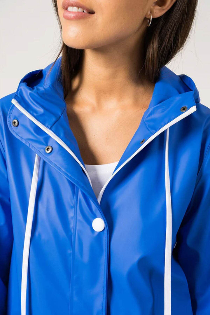 Femme portant un imperméable bleu vif Ste Gaia, parfait pour le printemps et résistant à l'eau.